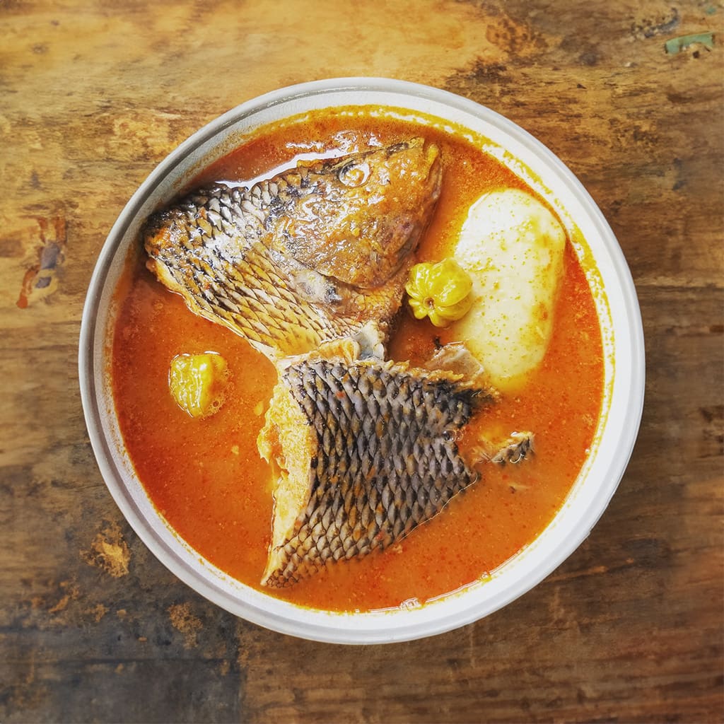 Ghanaian Fufu, a smooth, dough-like consistency staple, served submerged in a rich fish stew, bursting vibrant local spices – a traditional and savory West African delicacy from Ghana.